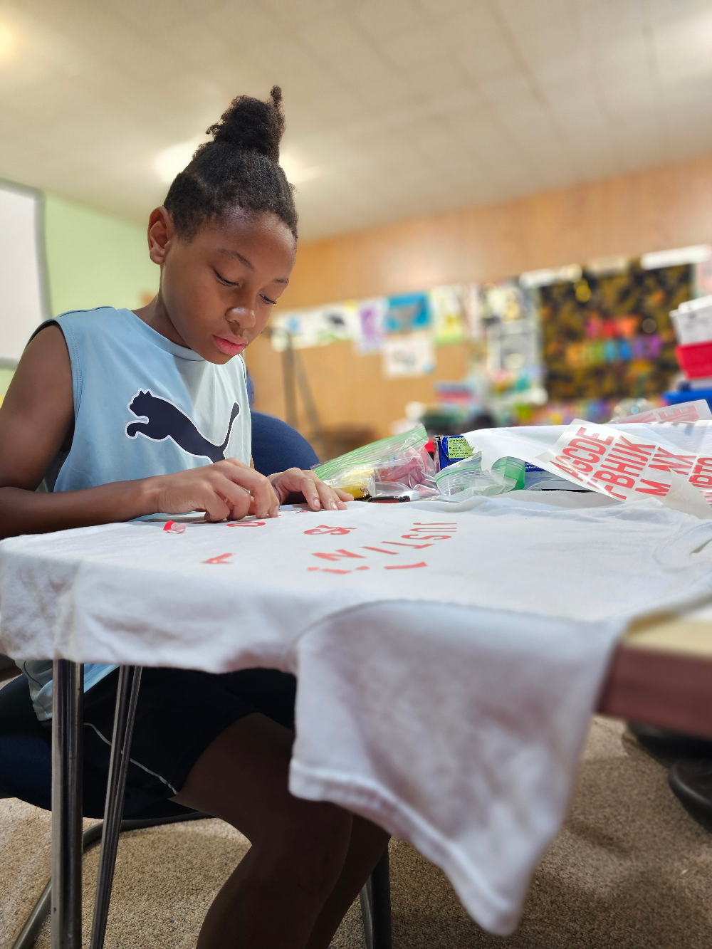 A student pressing vinyl letters onto a t-shirt